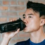 A guy drinking from a black water bottle