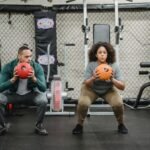 Two people squatting with medicine balls